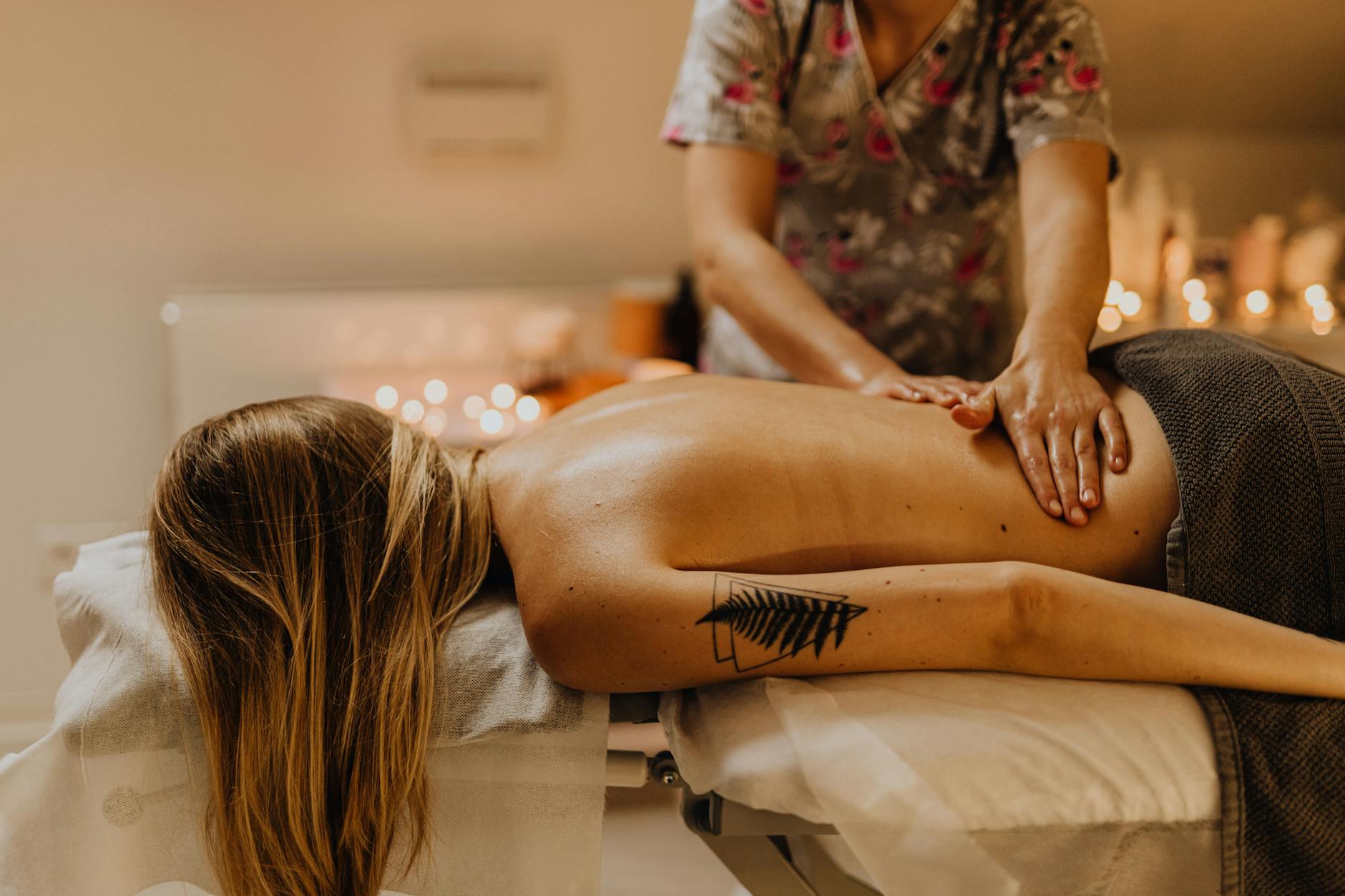 a tattooed woman getting a back massage